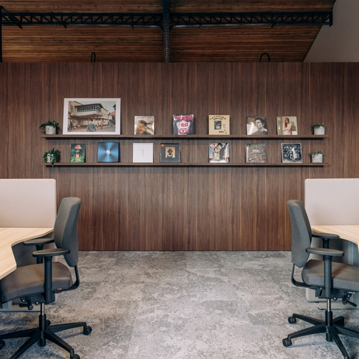 Modern office space with wooden wall, shelves with decorative items, and chairs.