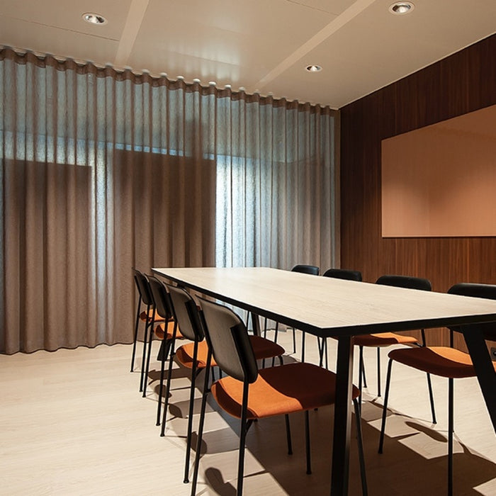 Modern conference room with long table and chairs near large windows.