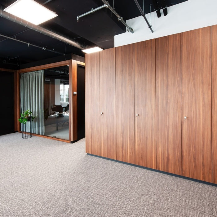 Modern office interior with wooden panel walls and a glass door.