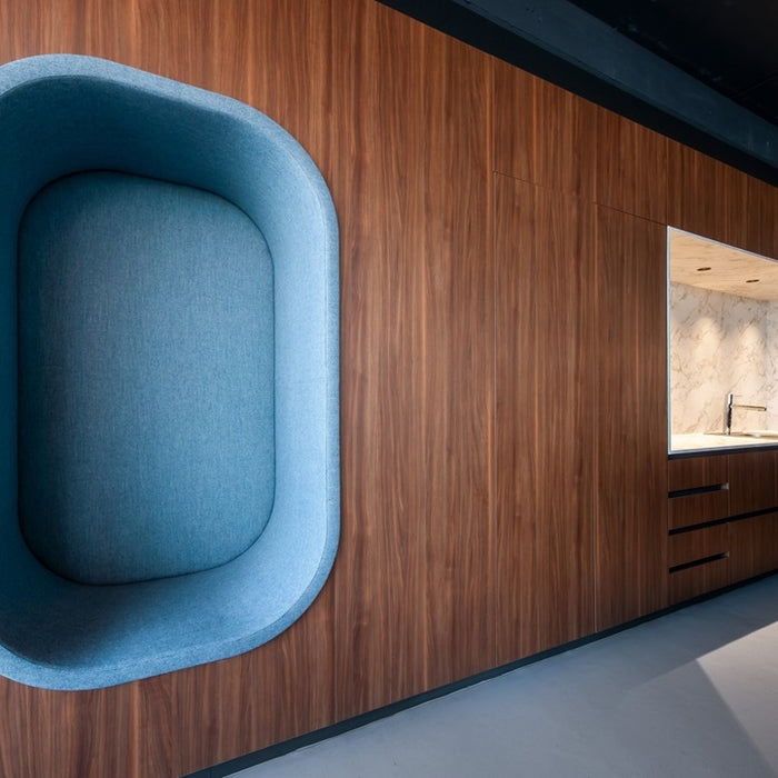 Blue cushioned chair against a wooden wall with a window in the background