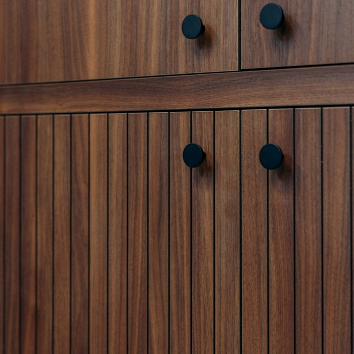 Close-up of a wooden cabinet with black knobs