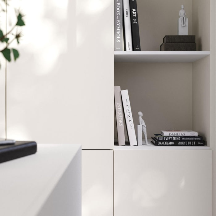 White bookshelf with books and decorative items against a neutral wall