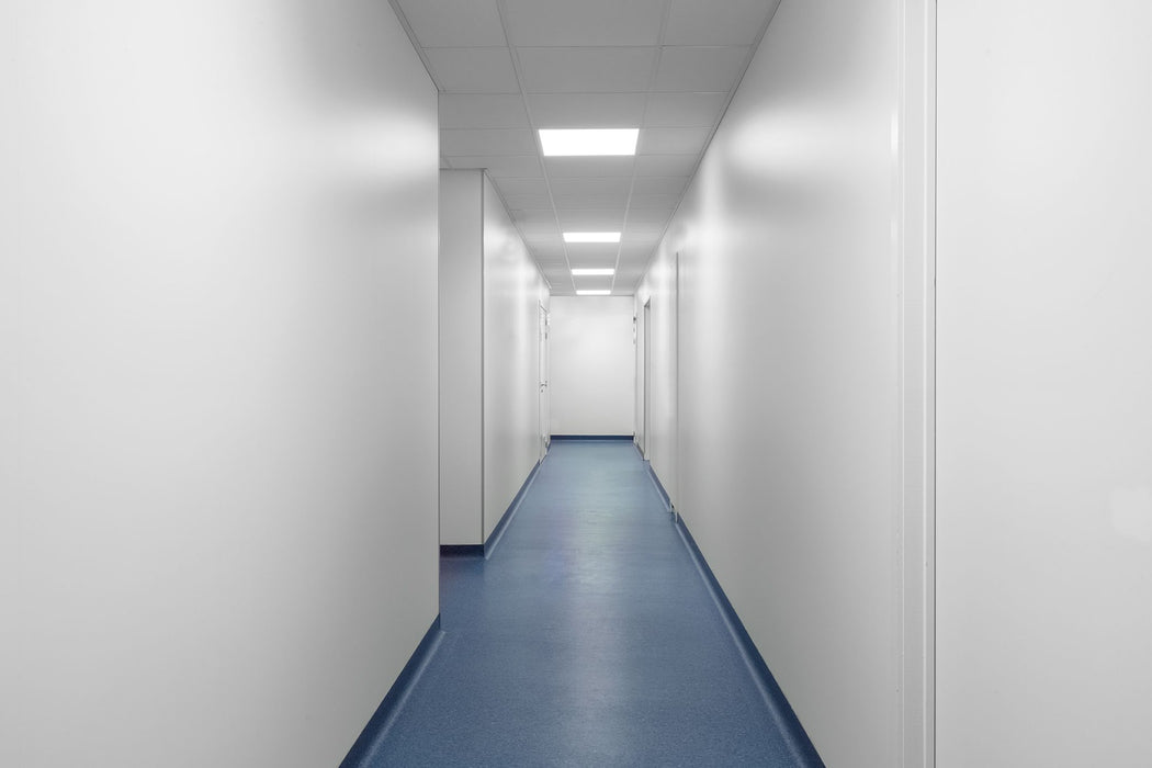 Long, narrow hallway with white walls and a blue floor.