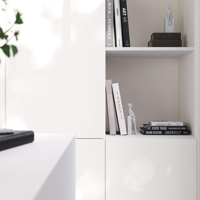 White bookshelf with books and decorative items against a light wall.