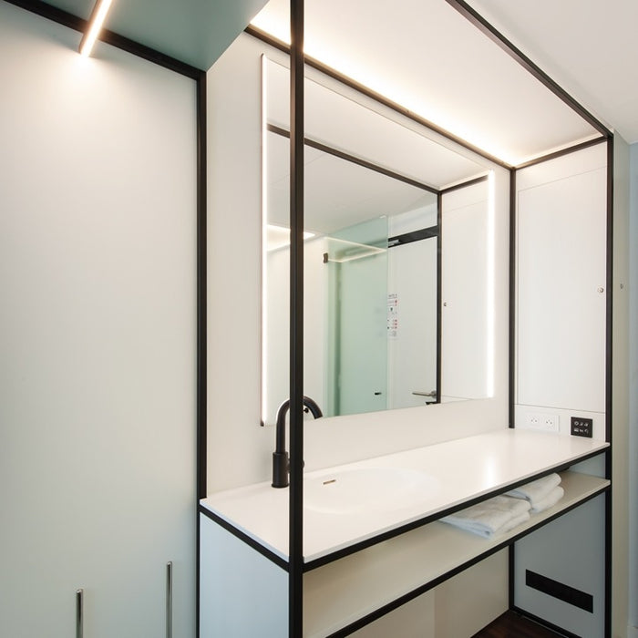 Modern bathroom vanity with illuminated mirror and white countertop.