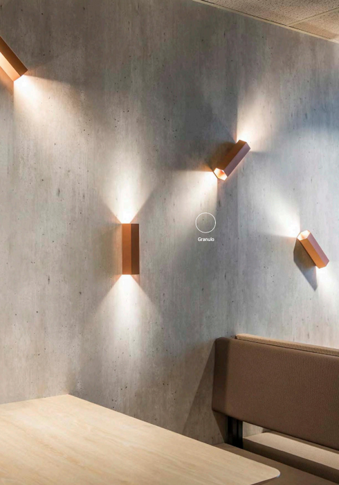 Modern wall lights on a concrete wall with a table and chair in the foreground.