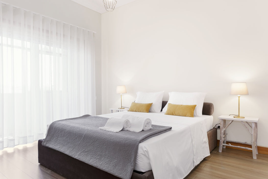 Modern bedroom with a neatly made bed, gray blanket, and two lamps on nightstands.